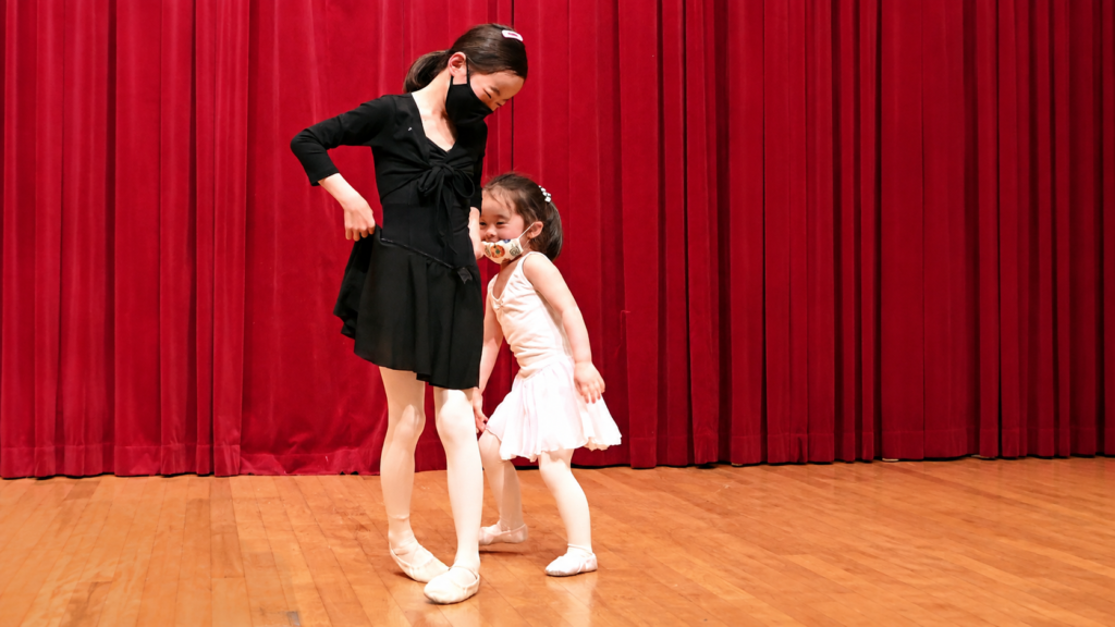 お姉さんのそばで安心した表情を見せる安城バレエの小さな子ども